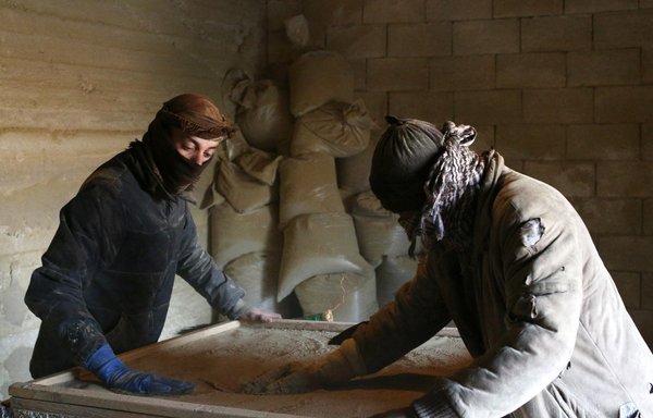 Men sift dried cannabis to prepare hashish in a garage in the village of Yamouneh in eastern Lebanon's Bekaa Valley, on March 29, 2021. [Dylan Collins/AFP]