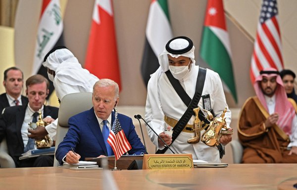 US President Joe Biden takes notes while an usher serves coffee during the Jeddah Security and Development Summit (GCC+3) at a hotel in Saudi Arabia's Red Sea coastal city of Jeddah on July 16. [Mandel Ngan/AFP]