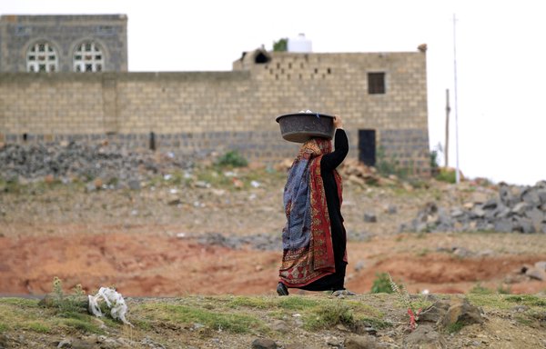 A Yemeni woman walks near the village of Hababah, about 45km south of Sanaa, on June 13, 2019. [Mohammed Huwais/AFP]