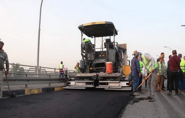 Workers spread asphalt on Mosul's Third Bridge on July 2, after the completion of repair work. [Ninawa province Facebook page]