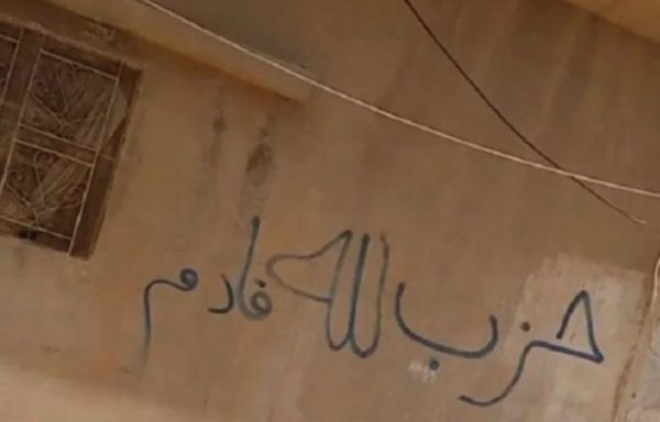 In this file photo, a graffito that reads 'Hizbullah is coming' is seen on the side of a house in the Deir Ezzor border town of Albu Kamal. [Jamil al-Abed]