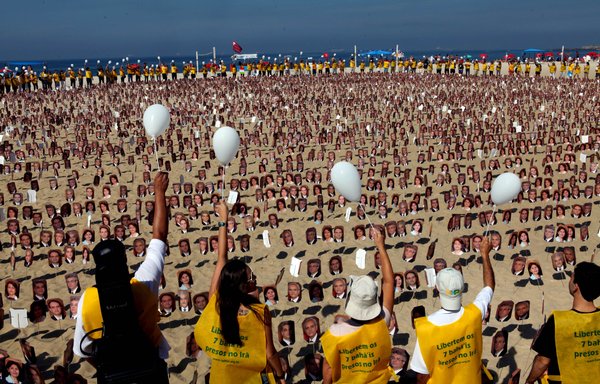 أفراد من الطائفة البهائية يتظاهرون على شاطئ كوباكابانا في ريو دي جانيرو بالبرازيل يوم 19 حزيران/يونيو 2011، مطالبين السلطات الإيرانية بإطلاق سراح سبعة سجناء بهائيين متهمين بالتجسس. [كارولينا فرنانديز/وكالة الصحافة الفرنسية]