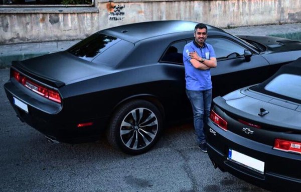 Shahram Poursafi shows off his American-made cars in a photo posted online in January 2018. The photo appears to have been taken in Iran, based on the graffiti behind him. [Shahram Poursafi Facebook account]