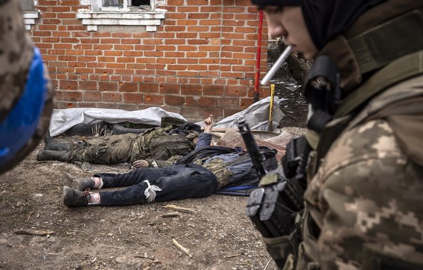 A Ukrainian soldier walks past the bodies of Russian soldiers after Ukrainian troops retook the village of Mala Rohan, east of Kharkiv, on March 30. [Fadel Senna/AFP]