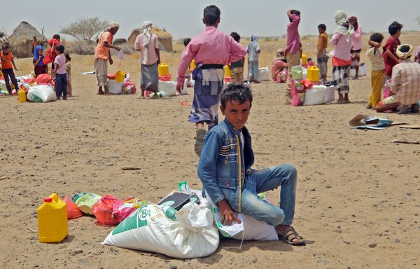 Yemenis displaced by the conflict receive food aid and supplies to meet their basic needs at a camp in Hays district in al-Hodeidah province on March 29. [Khaled Ziad/AFP]