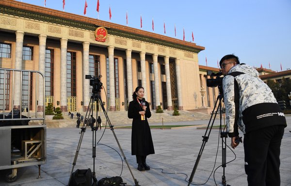 Journalists work in front of the Great Hall of the People before the second plenary session of China's National People's Congress in Beijing on March 8. [Leo Ramirez/AFP]
