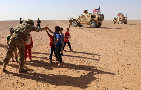 Children in al-Rukban camp, near al-Tanf base, greet a US soldier on August 18. [US Army Commandos/Facebook]