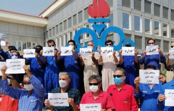 Iranian oil and gas sector employees hold signs reading 'Section 10 is our legal right,' in February, demanding that the government implement legislation passed in 2014 and raise their salaries. [Iran International]