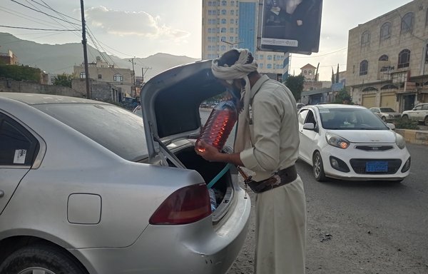 تاجر يبيع المشتقات النفطية يضع في صندوق سيارته حاوية صغيرة تحتوي على وقود عالي الكلفة. [هيثم محمد/المشارق]