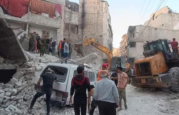 Aleppo residents stand amid the rubble of a building that collapsed on September 7. Signs of neglect are evident in the regime-controlled district. [Deir Ezzor Moment by Moment Facebook page]