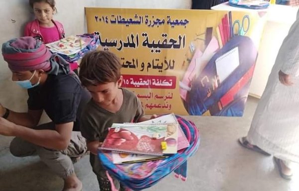 انجمن قتل‌عام شعیطات با حمایت ائتلاف بین‌المللی از خانواده‌های کشته‌شدگان به‌دست داعش حمایت می‌کند. در این عکس که روز ٢۰ شهریورماه ١٤۰۰ گرفته شده است، کیف‌ مدرسه بین کودکان استان دیرالزور توزیع می‌شود. [صفحۀ فیس‌بوک الشعیطات مدیناتی]