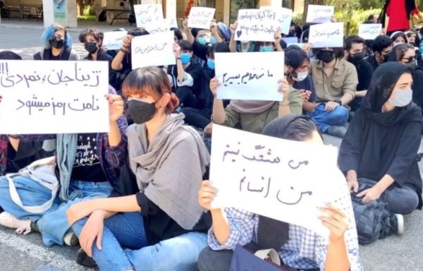 A group of Iranian students, some with uncovered hair, hold signs that read 'We don't want to die', 'I'm a person, not a hashtag', and a tribute to Mahsa Amini, whose September 16 death sparked the ongoing protests. [Social media]