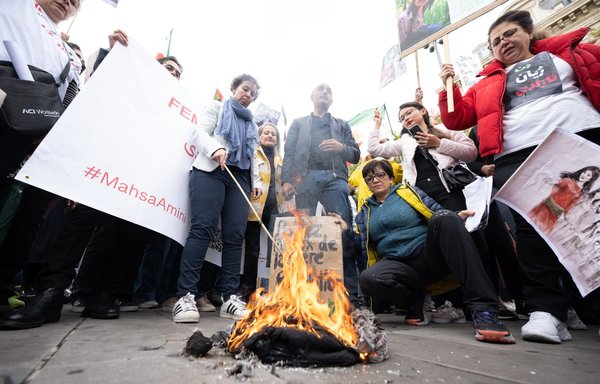 Women burn headscarves during a demonstration in support of Mahsa Amini on October 2 in Paris. [Stefano Rellandini/AFP]