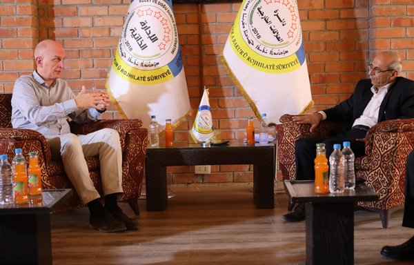 Kurt Stokel Stilfried of the German Foreign Ministry (L) meets with Syrian Democratic Forces representative Fener Kait on October 6, during the process of the repatriation of German citizens from Roj camp in northeastern Syria. [Executive Council of North and East Syria]