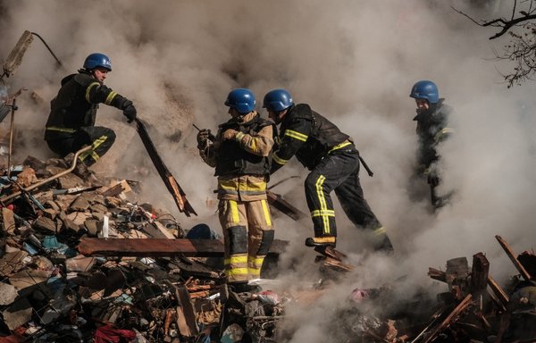 Ukrainian firefighters work on a destroyed building after a drone attack in Kyiv on October 17. Officials said Kyiv had been struck four times in an early morning Russian attack with Iranian drones that damaged a residential building and targeted the central train station. [Yasuyoshi Chiba/AFP]
