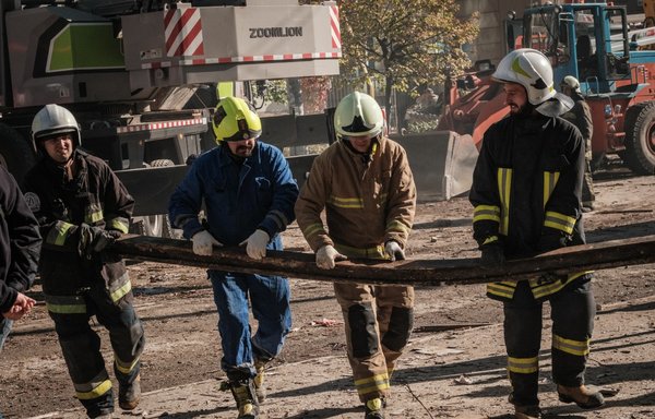 Ukrainian firefighters carry debris after a drone attack in Kyiv on October 17, amid the Russian invasion of Ukraine. Ukraine officials said Kyiv had been struck four times in an early morning Russian attack with Iranian drones that damaged a residential building and targeted the central train station. [Yasuyoshi Chiba/AFP]