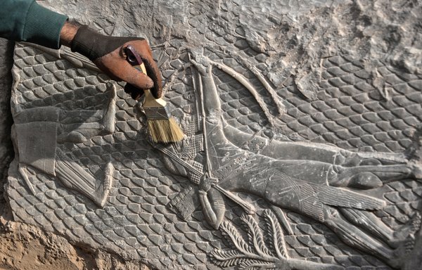 An Iraqi worker excavates a rock-carving relief recently found at the Mashki gate, one of the monumental gates to the ancient Assyrian city of Ninawa, on October 19. [Zaid al-Obeidi/AFP]