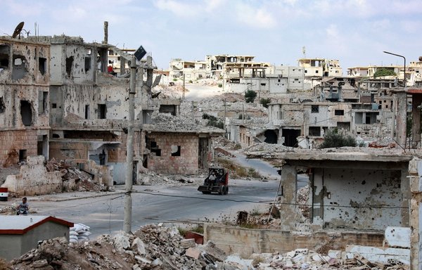 A bulldozer in the midst of destruction in the district of Daraa al-Balad of Syria's southern city of Daraa, on September 12, 2021. [Louai Beshara/AFP]