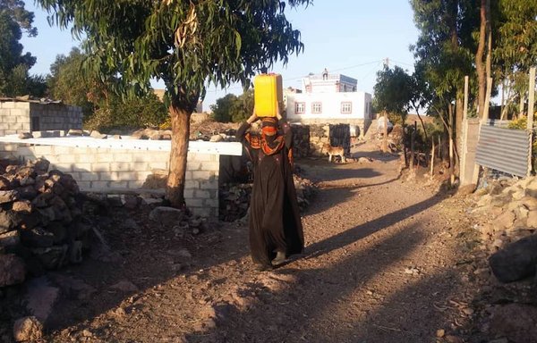 Dalila Salih, a resident of the Ibb province village of Dharah, fetches drinking water each day, carrying it on her head for long distances. [Haitham Mohammed/Al-Mashareq]