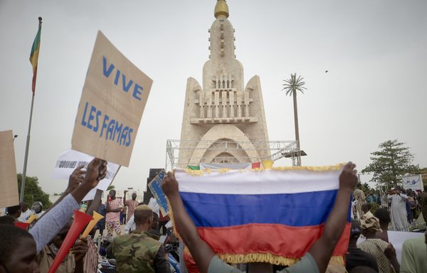 Supporters of Malian Armed Forces (FAMA) hold a Russian flag as they gather at Independence square in Bamako on May 28, 2021 to celebrate the recent coup led by the vice president of the transitional government Assimi Goita. [Michele Cattani/AFP]