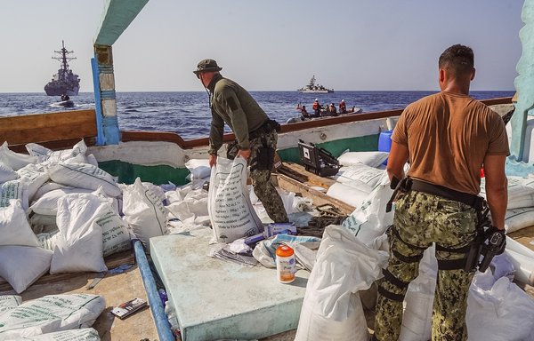 Guided-missile destroyer USS The Sullivans and patrol coastal ship USS Hurricane sail in the background as sailors inventory a large quantity of urea fertiliser and ammonium perchlorate discovered on board a fishing vessel intercepted by US naval forces while transiting international waters in the Gulf of Oman on November 9. [US Navy]