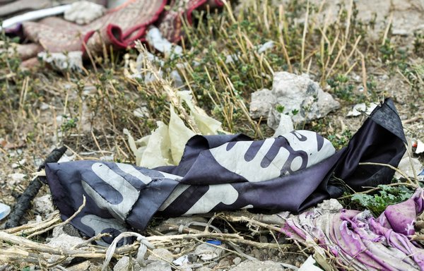 This picture taken March 24, 2019, shows a discarded ISIS flag lying on the ground in the village of al-Baghouz in Syria's Deir Ezzor province, a day after the declaration of the group's defeat by the international coalition backed Syrian Democratic Forces. [Guiseppe Cacace/AFP]