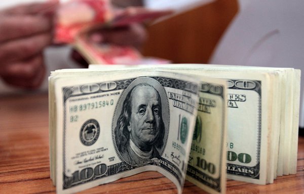 An Iraqi man counts money behind a pile of American dollars in his currency exchange bureau in Baghdad on April 11, 2012. The US military's reward programme offers generous rewards for information about adversarial actors in the region. [Ali al-Saadi/AFP]