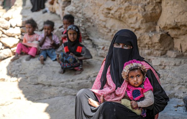 A Yemeni family sits outside a cave where they sought refuge from poverty and lack of housing, west of Taez. [Ahmad al-Basha/AFP]