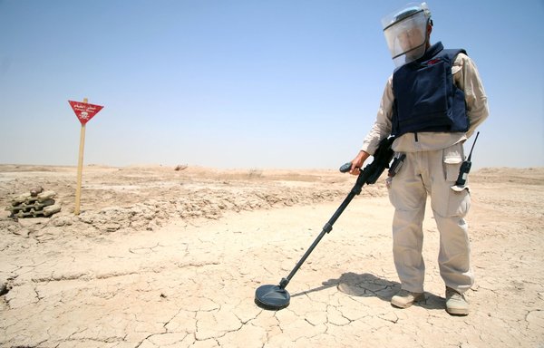 An Iraqi man wearing protective gear searches for land mines at the Shalamja border crossing, west of Basra, on the border between Iraq and Iran, on June 10, 2015. [Haidar Mohammed Ali/AFP]