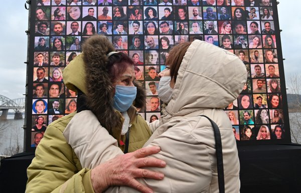 Relatives react in front of a screen bearing portraits of crew members and passengers of Ukraine International Airlines Flight 752, who were killed when the flight was shot down over Iran on January 8, 2020, during a memorial ceremony in Kyiv on the first anniversary of the crash. [Genya Savilov/AFP]
