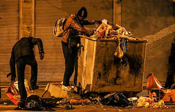 Poverty-stricken residents of Tehran dig through trash in the streets. [DW]