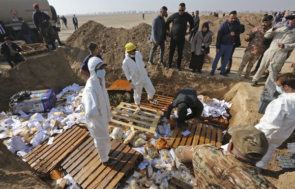 Iraqi government officials wearing white coveralls and face masks prepare to destroy nearly six tonnes of drugs in Baghdad's Nahrawan area on December 18. [Sabah Arar/AFP]