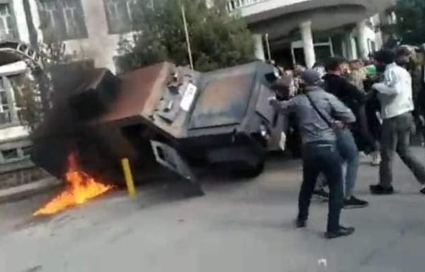 Protesters destroy an armoured vehicle in front of the Sweida local government building on December 4. [@M_Alneser/Twitter]