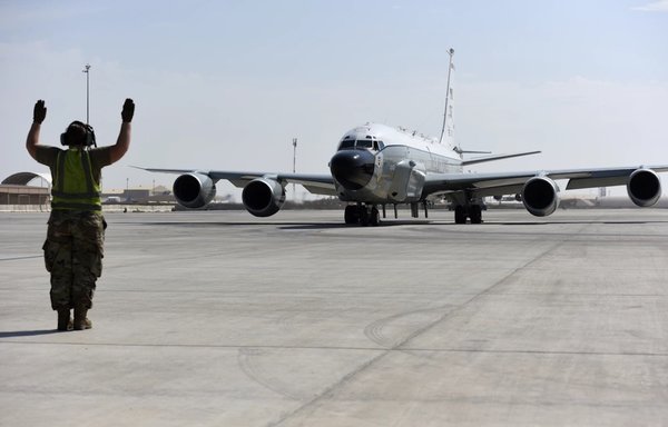 A crew chief assigned to the 763rd Expeditionary Reconnaissance Squadron directs an RC-135 Rivet Joint from its parking area in preparation for a mission at al-Udeid Air Base in Qatar on November 21, 2019. [US Air Force]