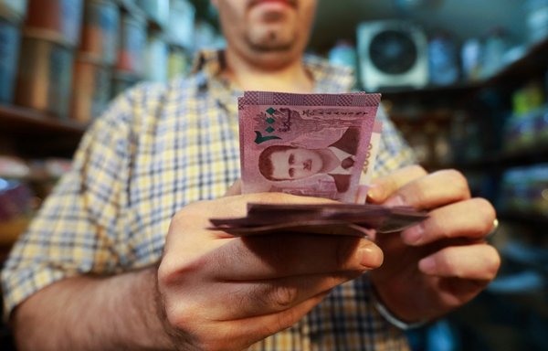 تاجر يعد أوراقا نقدية بالليرة السورية عليها صورة الرئيس السوري بشار الأسد في سوق البزورية بدمشق يوم 11 أيلول/سبتمبر 2019. [لؤي بشارة/وكالة الصحافة الفرنسية]