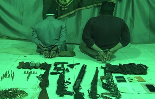 Two ISIS detainees are seen with weapons, ammunition and forged documents seized during Operation Al-Jazeera Thunderbolt on January 4. [SDF Press Centre]