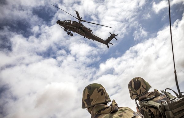 A US Army AH-64 Apache attack helicopter flies over members of the Moroccan Royal Armed Forces during the second annual African Lion military exercise in the Tan-Tan region in southwestern Morocco last June 30. [Fadel Senna/AFP]