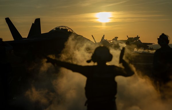 A US sailor signals to an F-18 as it taxis along the runway of the USS Nimitz in the South China Sea on January 20. [US Navy]