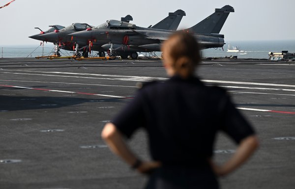 A French Navy sailor stands in front of Rafale fighter jets on the deck of the Charles de Gaulle aircraft carrier during the Indo-French Varuna joint naval exercise at Mormugao harbour in Goa state, India, on January 21. [Sajjad Hussain/AFP]