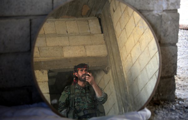 A member of the Kurdish People's Protection Units communicates via radio in the Syrian city of al-Raqa's eastern al-Sinaa district, on June 21, 2017. [Delil Souleiman/AFP]