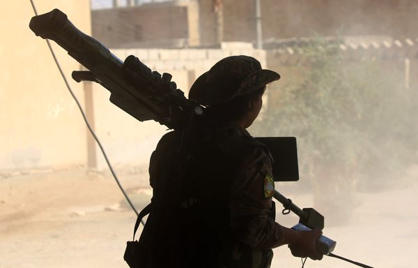 A member of the Kurdish People's Protection Units (YPG) carries a weapon in al-Sinaa district of the Syrian city of al-Raqa on June 21, 2017, during an offensive to retake the city from ISIS. [Delil Souleiman/AFP]