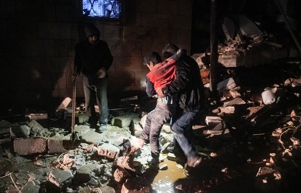A man carries away an injured child following an earthquake in the town of Jandaris, in Syria's northwestern city of Afrin in the opposition-held part of Aleppo province, early February 6. [Rami al-Sayed/AFP]