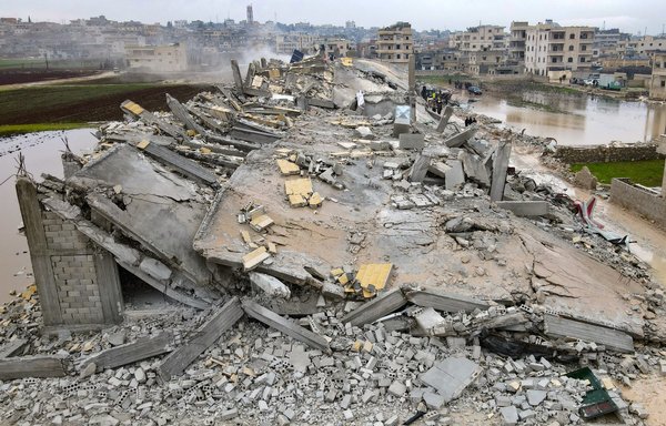 This aerial view shows residents helped by bulldozers, searching for victims and survivors in the rubble of collapsed buildings, following an earthquake in the town of Sarmada in the northwestern Syrian province of Idlib, early on February 6. [Muhammad Haj Kadour/AFP]