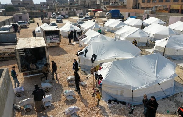 White Helmets rescue workers distribute aid on February 11 in a makeshift camp near Killi in Syria's Idlib province, where volunteers have set up tents to temporarily shelter survivors who have become homeless after an earthquake hit the area. [Omar Haj Kadour/AFP]