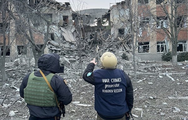 An investigator from the Office of the Prosecutor at the International Criminal Court and a Ukrainian security officer stand beside a residential complex destroyed by Russian missiles in Kharkiv, Ukraine. [Office of the Prosecutor at the International Criminal Court Telegram account]