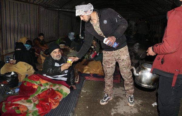 A member of the SDF-affiliated Manbij Military Council on February 7 offers hot drinks to Syrians displaced by an earthquake the day prior. [Women's Military Council for the city of Manbij and its Countryside]