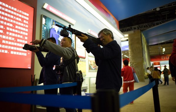 This picture taken on October 10, 2017, shows visitors using a weapon simulator during an exhibition at the Beijing Exhibition Centre. [Wang Zhao/AFP]
