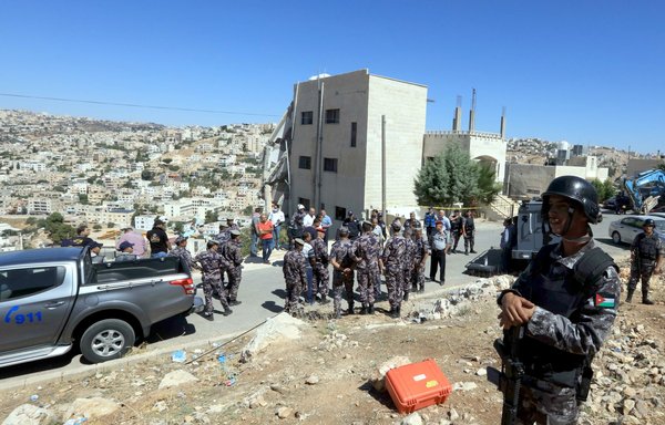 Jordanian security forces gather near a damaged building in Salt on August 12, 2018. Jordanian forces killed three 'terrorists' and arrested five others during a raid they staged after an officer was killed in a bomb blast near Amman a day earlier. Three members of the security forces died during the raid, and another later succumbed to his injuries. [Khalil Mazraawi/AFP]