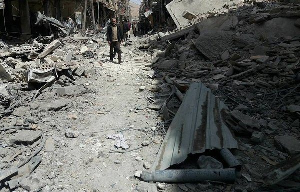 Syrians walk through a destroyed neighbourhood in the wake of the chemical attack on Douma in 2018. [Douma City Co-ordination Committee]