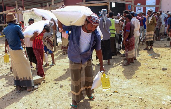 Displaced Yemenis receive humanitarian aid provided by the World Food Programme in Yemen's northern province of Hajjah on January 22. [Essa Ahmed/AFP]